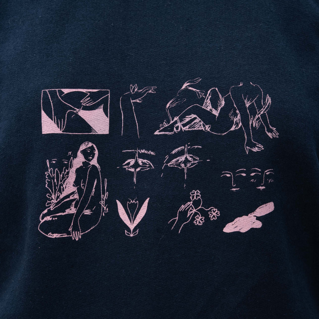 A close-up of a dark navy blue t-shirt featuring a light pink graphic print on the chest. The print consists of multiple minimalist line-art illustrations, including faces, hands, abstract shapes, and a seated figure.