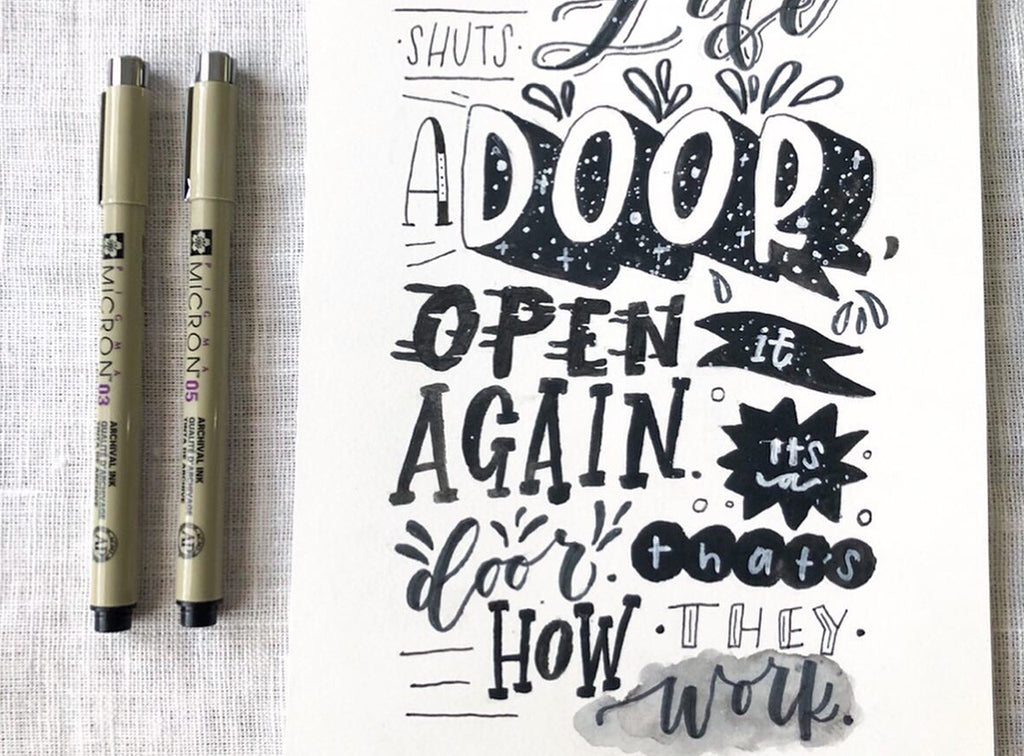 Two markers next to a piece of paper with handwritten text on a textured surface