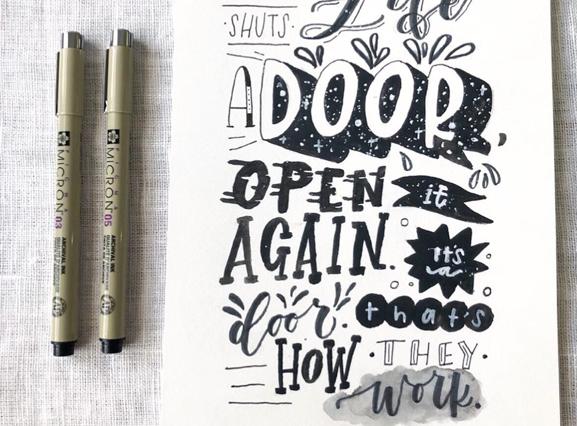 Two markers next to a piece of paper with handwritten text on a textured surface